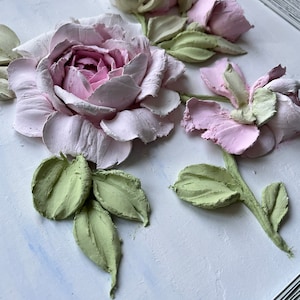 Peut inclure: Une &oelig;uvre d'art murale 3D encadr&eacute;e repr&eacute;sentant des roses roses et blanches avec des feuilles vertes. Les roses sont sculpt&eacute;es et ont une texture r&eacute;aliste.