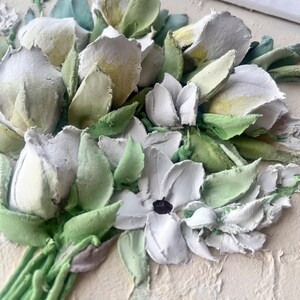 May include: A close-up of a 3D floral painting featuring white and green flowers. The flowers are crafted from textured paint and appear to be arranged in a bouquet.