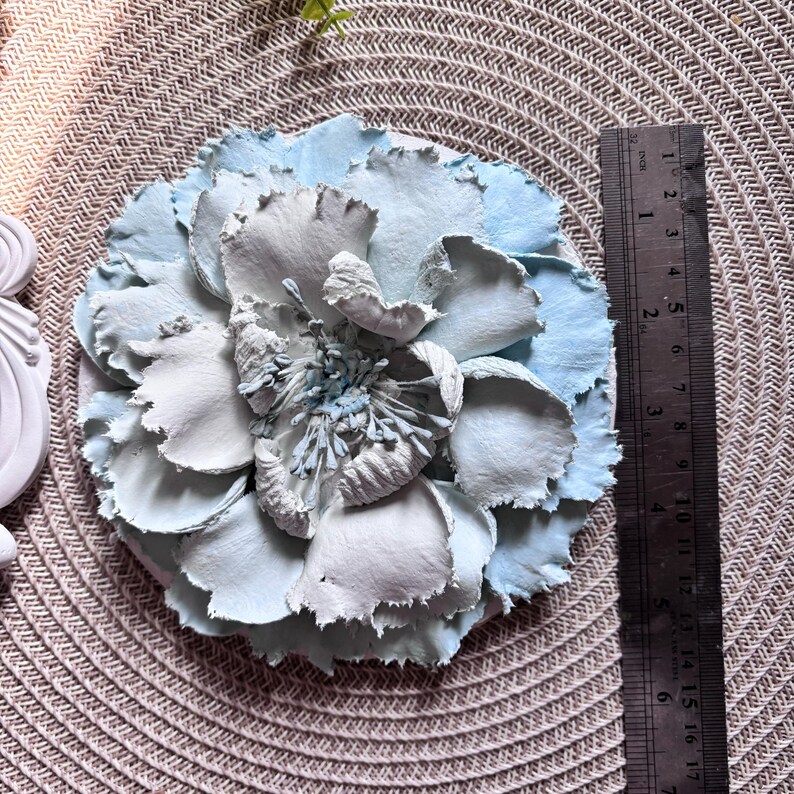 以下が含まれることがあります： テクスチャ加工が施された薄い青と白の紙の花。花は直径約15cmです。