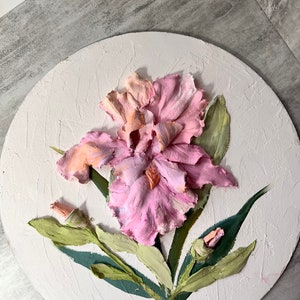 K&ouml;nnte beinhalten: Eine rosa und orangefarbene Iris-Blume mit gr&uuml;nen Bl&auml;ttern, die auf eine runde Leinwand gemalt ist.