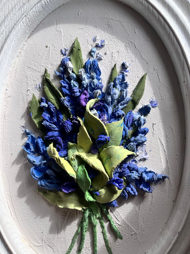 May include: A close-up of a 3D painting depicting a bouquet of blue and green flowers. The flowers are painted in a realistic style and have a textured surface.