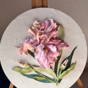 K&ouml;nnte beinhalten: Ein rundes Leinwandbild mit einer rosa Iris-Blume mit gr&uuml;nen Bl&auml;ttern und Knospen. Die Blume ist in einem realistischen Stil mit strukturierter Farbe gemalt.