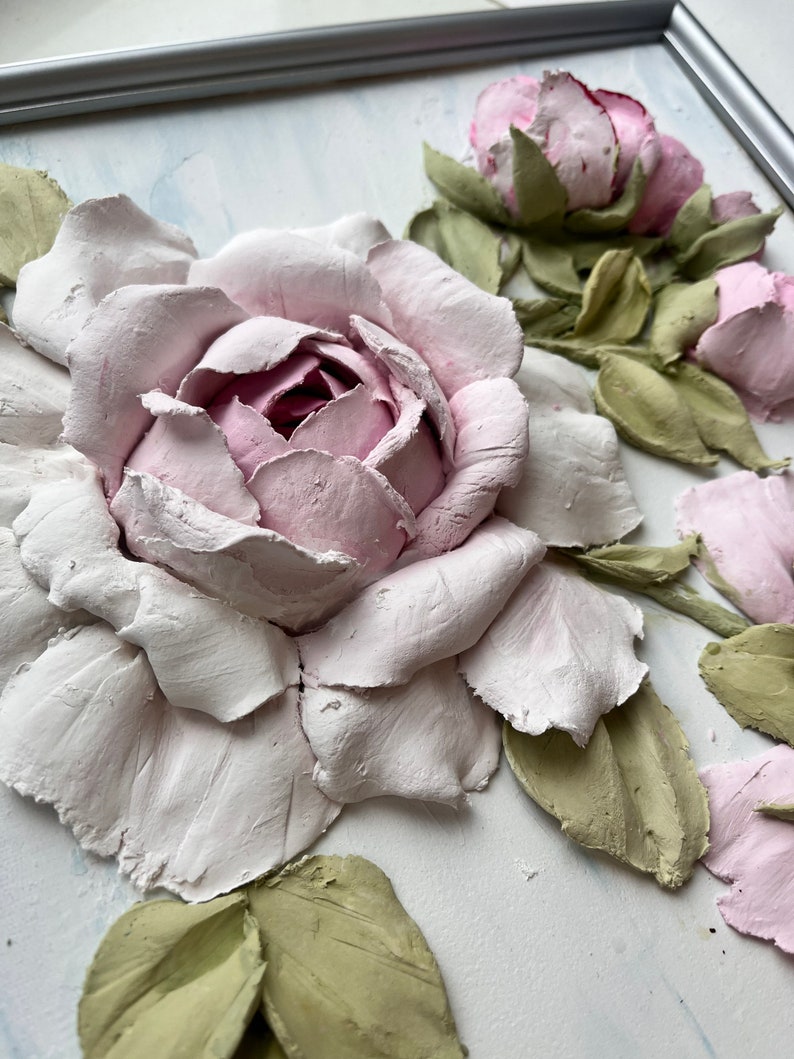 Peut inclure: Une &oelig;uvre d'art murale 3D repr&eacute;sentant une grande rose rose avec des feuilles vertes. La rose est faite d'argile textur&eacute;e et a une apparence r&eacute;aliste.