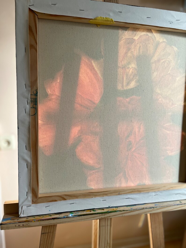 Puede incluir: Un primer plano de una pintura sobre lienzo con un marco de madera. La pintura presenta un dise&ntilde;o suave y abstracto de flores rosas y blancas. El lienzo est&aacute; estirado sobre el marco y asegurado con grapas.