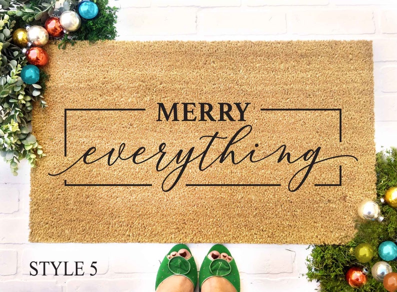 May include: A brown coir doormat with the text "MERRY everything" in a black rectangular frame.