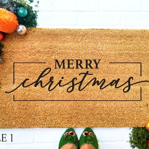 May include: A brown coir doormat with the text "MERRY christmas" in black lettering inside a black frame.