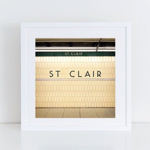 May include: A framed photograph of a subway station entrance with yellow tiled walls and a black sign that reads "ST CLAIR".