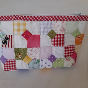 May include: A patchwork zippered pouch with a red and white gingham trim. The pouch is made of various fabrics in shades of pink, green, yellow, and purple.