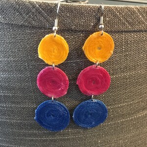 May include: A pair of earrings with three circular elements each. The top element is yellow, the middle is red, and the bottom is blue.