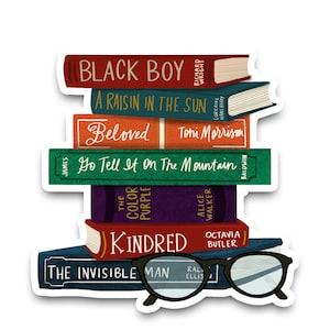 May include: A stack of vintage paperback books with colorful covers and titles including "Black Boy", "A Raisin in the Sun", "Beloved", "Go Tell It on the Mountain", "The Color Purple", "Kindred", and "The Invisible Man". A pair of black-rimmed glasses is resting on top of the books.
