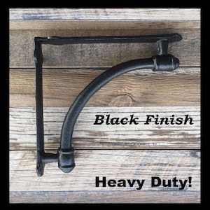 May include: Black metal shelf bracket with a curved arm and a decorative finial. The bracket is heavy duty and has a black finish.