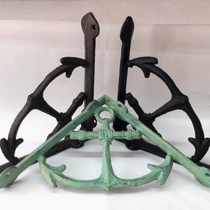 May include: Two black cast iron shelf brackets in the shape of an anchor, with a green cast iron anchor in the center.