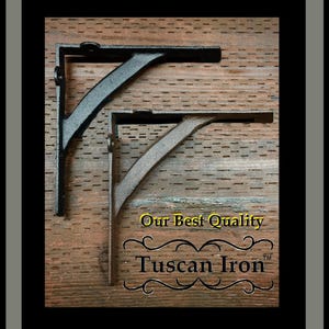 May include: Two black metal shelf brackets on a wood background. The brackets are in the shape of an L. The text "Our Best Quality Tuscan Iron™" is below the brackets.