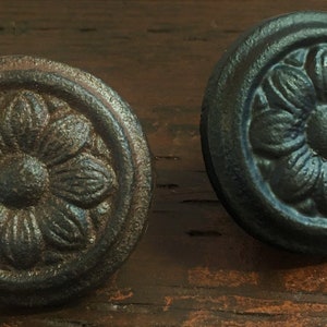 May include: Two black cast iron drawer pulls with a floral design. The pulls have a slightly distressed finish.