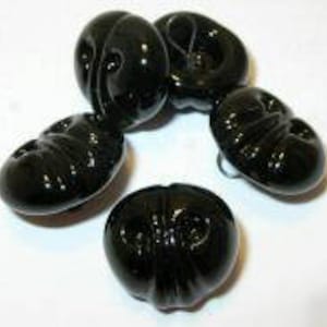 May include: Four black plastic buttons with a raised design. The buttons are round and have a shiny finish.