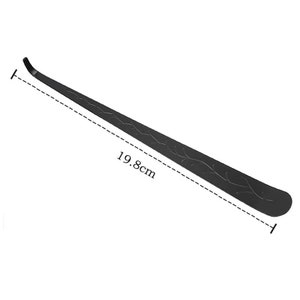May include: A black metal shoehorn with an ornate design. It measures 19.8 cm long.