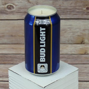 May include: A blue and gold Bud Light can candle with a white wax top and a black wick. The can has the words "Bud Light" and "Kickoff" printed on it.