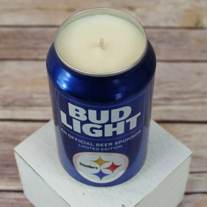 May include: A blue and white Bud Light can candle with the text "An Official Beer Sponsor Limited Edition" and the Pittsburgh Steelers logo.