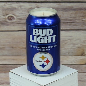 May include: A blue and silver can candle shaped like a Bud Light beer can with the text "Bud Light" and "An Official Beer Sponsor Limited Edition". The can has a Steelers logo with the text "Steelers" on it.