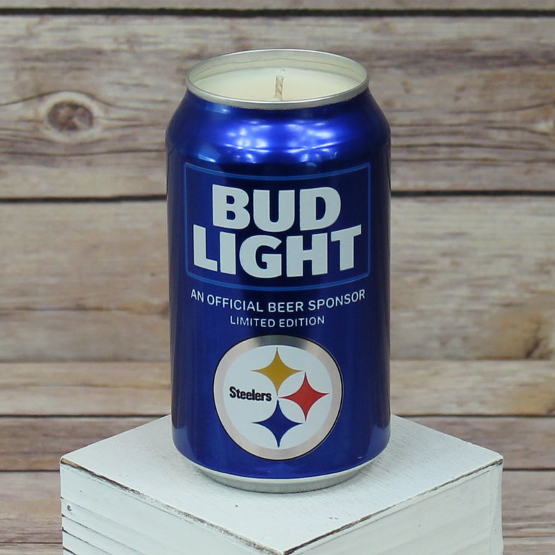 May include: A blue and silver can candle shaped like a Bud Light beer can with the text "Bud Light" and "An Official Beer Sponsor Limited Edition". The can has a Steelers logo with the text "Steelers" on it.