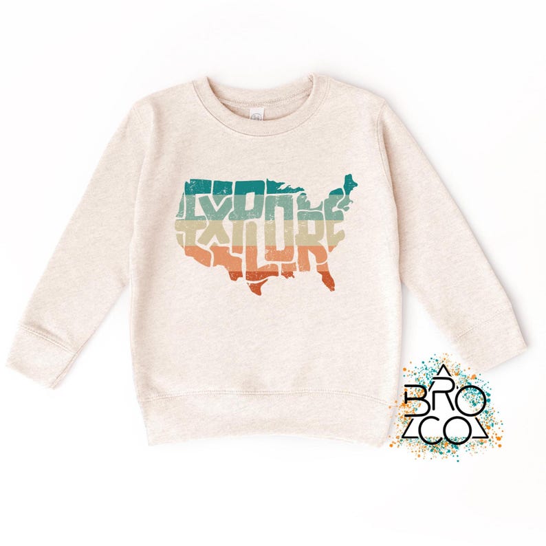 May include: A heathered beige long-sleeve sweatshirt featuring a graphic of the United States map filled with the word EXPLORE in horizontal stripes of teal, cream, and orange. The logo BRO CO is printed in the bottom right corner.