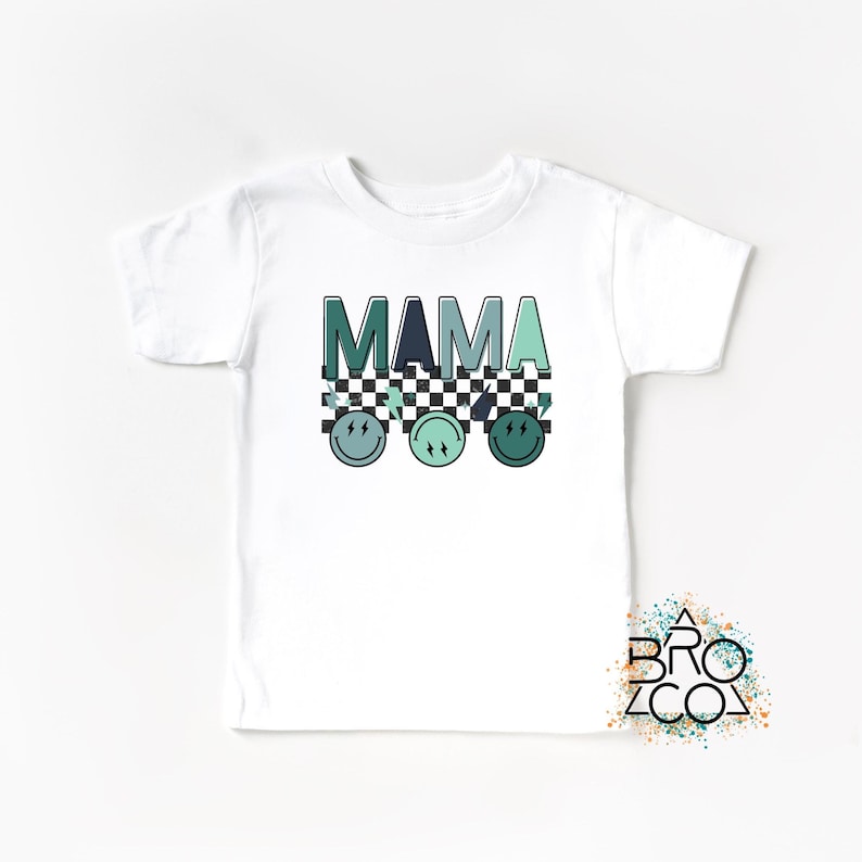 May include: White t-shirt with the word "MAMA" in green and blue letters with a checkered pattern and three green and blue smiley faces underneath.