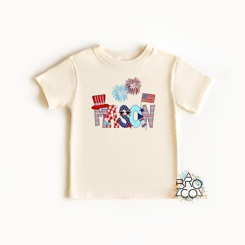 May include: A white t-shirt with a red, white, and blue design featuring the name "MASON" in large letters with stars, stripes, and fireworks.