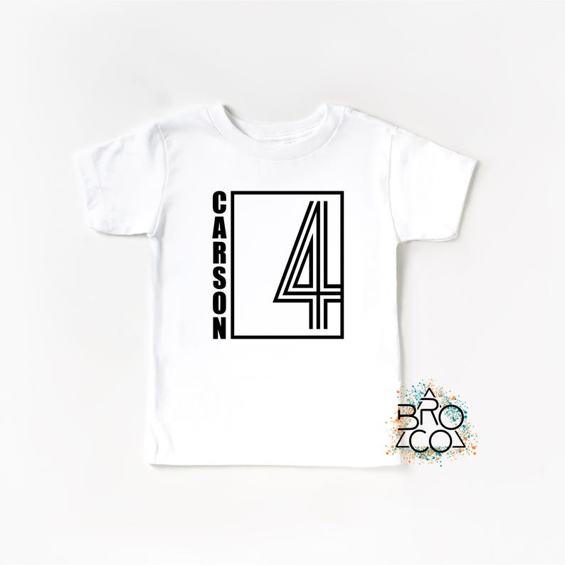 May include: A white short-sleeved t-shirt featuring a black graphic design on the front. The design consists of a rectangular frame containing the number 4 and the name CARSON written vertically in a bold, sans-serif black font.