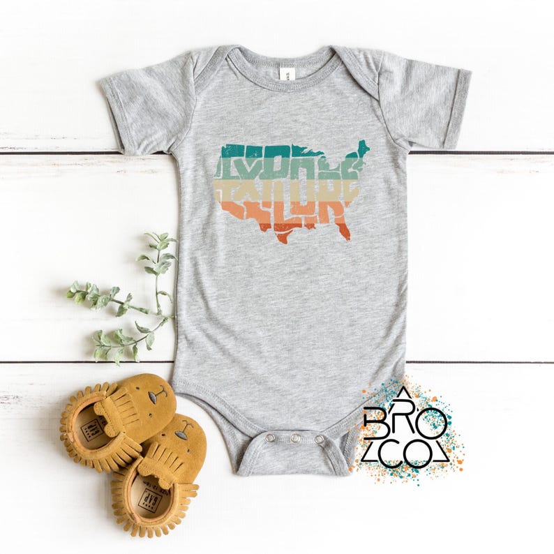 May include: A heather gray short-sleeve baby bodysuit featuring a graphic of the United States map in horizontal stripes of teal, beige, and orange. The bodysuit has a crew neckline and three metal snaps at the bottom crotch area.