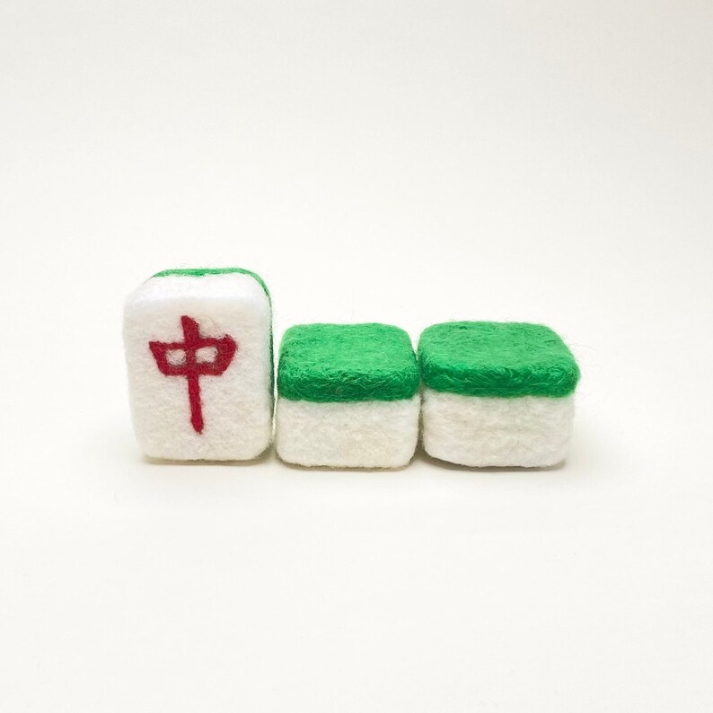 May include: Three felt mahjong tiles. One tile has a red Chinese character on a white background. The other two tiles have a green top and a white bottom.
