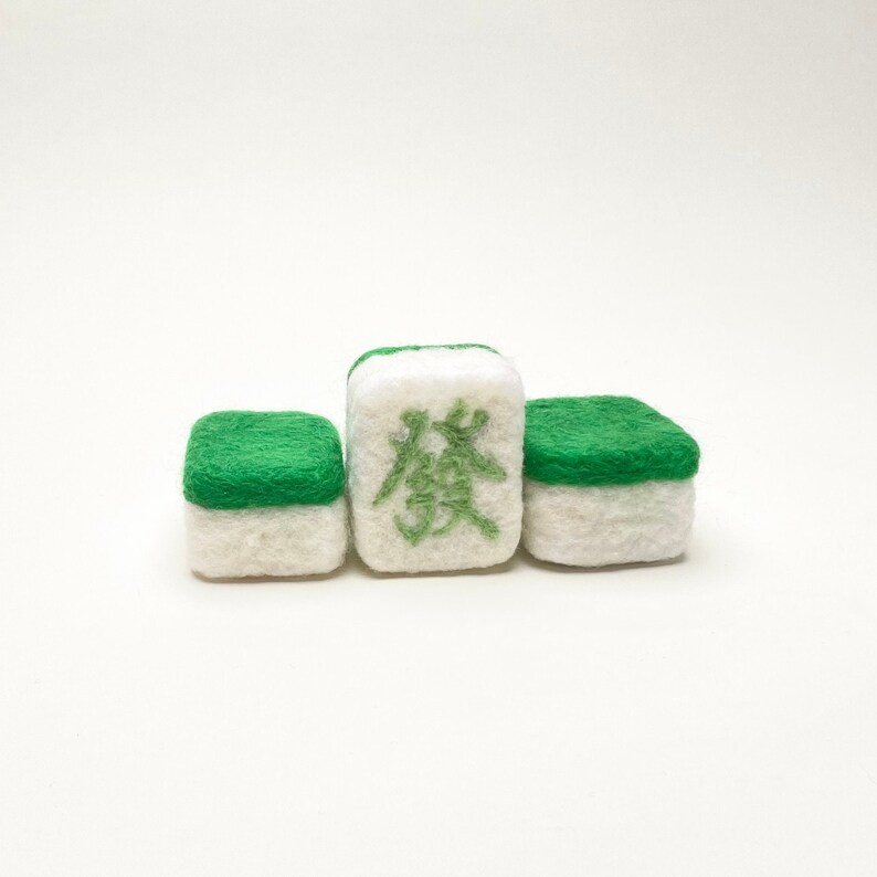 May include: Three white and green felt mahjong tiles. The centre tile has the Chinese character "發" in green.