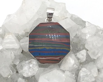 May include: A silver pendant with a multi-colored, striped, octagonal stone. The stone has shades of red, blue, green, and brown.