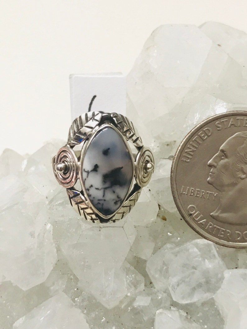Pu&ograve; includere: Un anello d'argento con una pietra di agata bianca e nera incastonata in un design d'argento dettagliato. L'anello &egrave; circondato da cristalli bianchi.