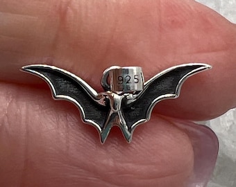 May include: A silver bat charm with black enamel wings and a 925 stamp.
