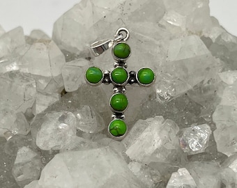 May include: A silver cross pendant with seven green turquoise stones.