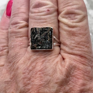 May include: A silver ring with a square black and silver gemstone. The gemstone has a unique pattern of silver flecks.