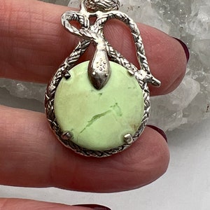May include: A silver pendant featuring a green serpentine stone set in a silver snake design.