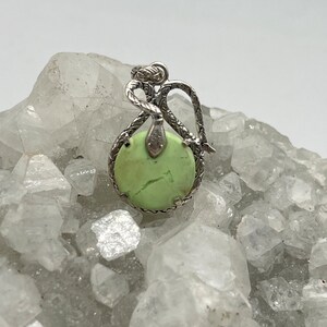 May include: A silver pendant featuring a green serpentine stone set in a silver snake design.