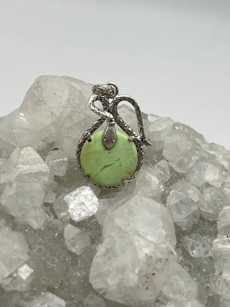 May include: A silver pendant featuring a green serpentine stone set in a silver snake design.