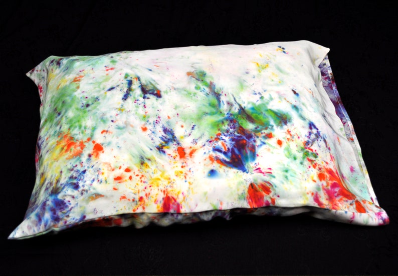 Puede incluir: Una funda de almohada blanca con un dise&ntilde;o abstracto colorido. El dise&ntilde;o presenta salpicaduras de pintura azul, verde, amarilla, naranja y roja.