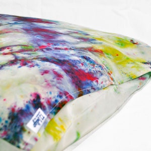 Puede incluir: Una funda de almohada blanca con un patr&oacute;n de te&ntilde;ido anudado colorido en tonos de rosa, azul, amarillo y verde. La funda de almohada tiene una etiqueta blanca con el texto "LTD" en ella.