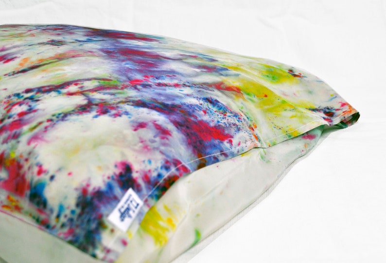 Puede incluir: Una funda de almohada blanca con un patr&oacute;n de te&ntilde;ido anudado colorido en tonos de rosa, azul, amarillo y verde. La funda de almohada tiene una etiqueta blanca con el texto "LTD" en ella.