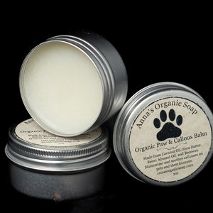 Puede incluir: Tres latas plateadas de bálsamo orgánico para patas y callos para perros. La etiqueta en la lata delantera dice "Anna's Organic Soap Organic Paw & Callous Balm Made from Coconut Oil, Shea Butter, Sweet Almond Oil, and Beeswax. Moisturizes and soothes callouses on pets' paws and their knuckles. annasorganicshop.com 2oz."
