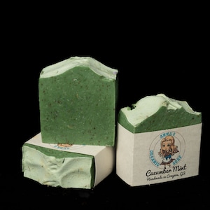 May include: Three bars of green soap with a white label that reads "Anna's Organic Soap Cucumber Mint Handmade in Conyers, GA".
