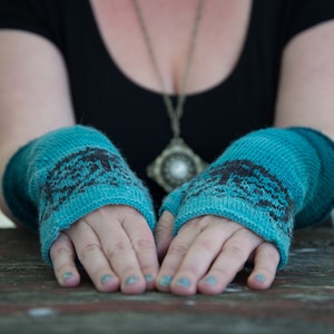 May include: A pair of teal blue knitted fingerless gloves with a black and white geometric pattern.