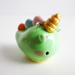 May include: A green unicorn charm with a gold spiral horn and colorful beads. The unicorn has pink ears and a pink and white face.