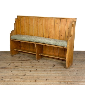 May include: A high-backed wooden bench constructed from light brown pine planks. The bench features a long, rectangular seat cushion upholstered in a sage green fabric with a repeating diamond pattern and a central support leg underneath.