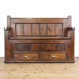 May include: A dark brown wooden bench with a high back and two drawers. The bench has a classic design with visible wood grain and brass drawer pulls. The bench includes armrests and a slatted back, offering a sturdy, traditional appearance.