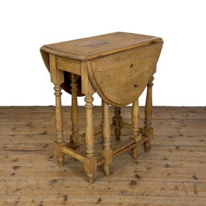 May include: A light brown oak drop-leaf table featuring a rectangular top with two hinged semi-circular side leaves. The table is supported by four turned legs connected by a lower rectangular stretcher frame, showcasing a natural wood grain finish.