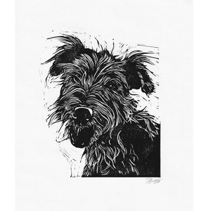 Puede incluir: Grabado en linóleo en blanco y negro de un perro con un pelaje peludo. El perro mira directamente al espectador con la boca ligeramente abierta. La impresión está firmada "T. Buggs" en la esquina inferior derecha.